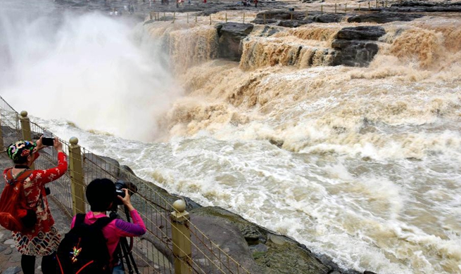 Tourists view Hukou Waterfall on Yellow River